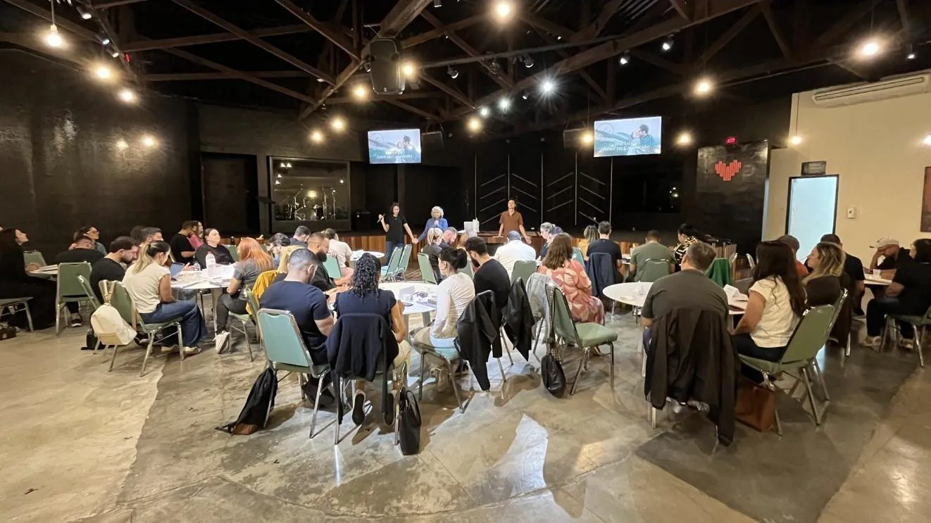 A Nothing Hidden workshop in progress: participants seated in small groups around round tables while the facilitators teach from the front